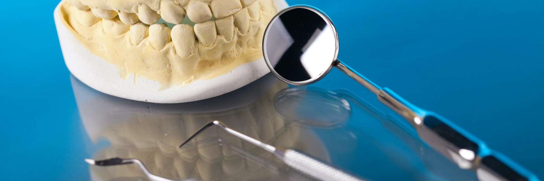 Molded teeth with mouth mirror and scalers on a table in Florida