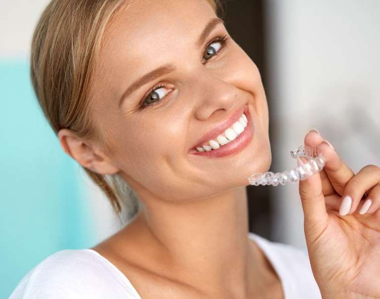  woman holding her aligner | Invisalign treatment in St Cloud FL