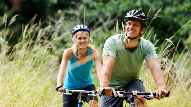 a couple smiling while riding a bicycle