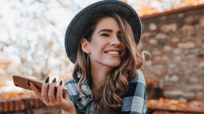woman wearing a hat holding a phone
